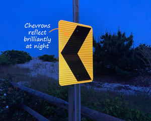 Road chevron sign reflects at night